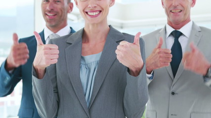 Wall Mural - Business people looking at camera with thumbs up 