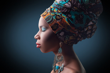 young beautiful fashion model with traditional african style with scarf, earrings and makeup on dark