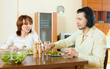 middle aged couple eating vegetarian salad with clear water in t