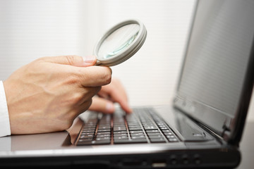 businessman is using magnifying glass on computer laptop. inte