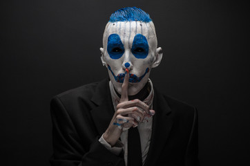 Wall Mural - Terrible clown and Halloween theme: Crazy blue clown in black suit isolated on a dark background in the studio