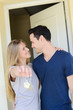 © W PRODUCTION - happy young couple man and woman handing over their new home keys in front of open house door