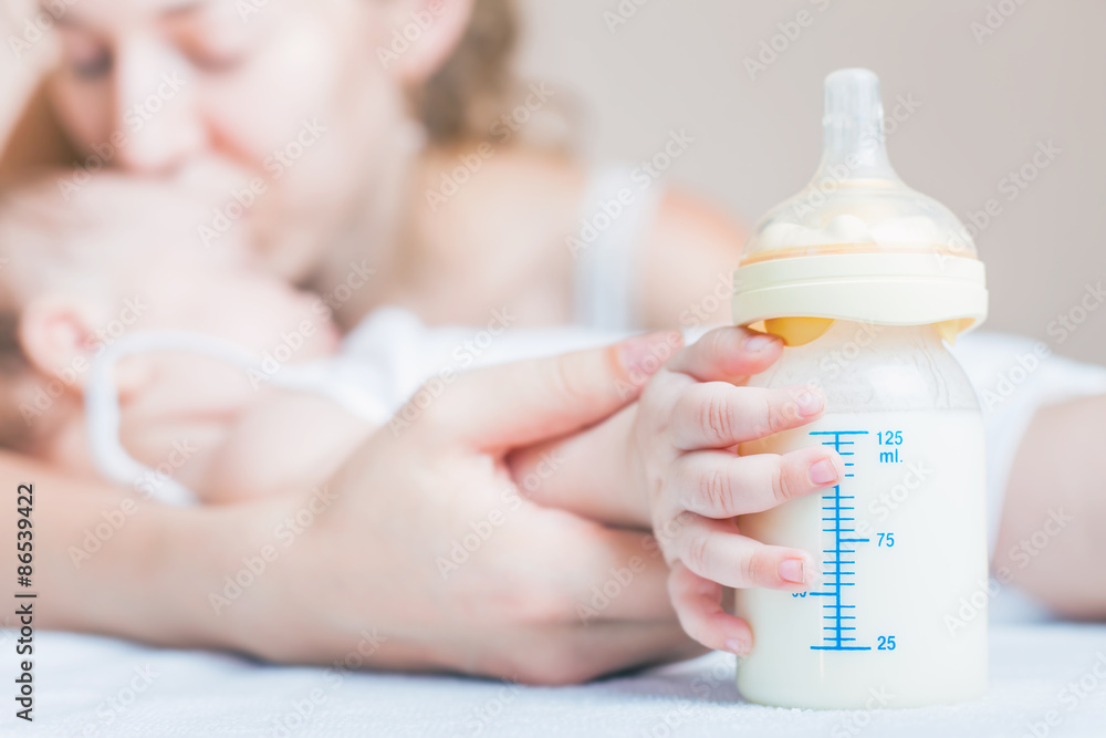 Baby holding a baby bottle with breast milk for breastfeeding. Mothers breast milk is the most healthy food for newborn baby. - obrazy, fototapety, plakaty 