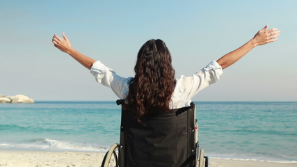 Wall Mural - Disabled woman with arms outstretched at the beach