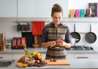 Elegant woman looking down while holding and slicing tomato