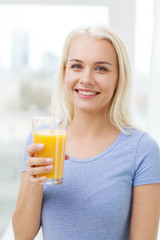 Wall Mural - smiling woman drinking orange juice at home