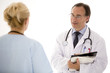 © cineberg - Male doctor with glasses holding his clipboard giving arrangements to a blond female colleague, back turned. Indoors