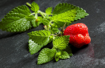 Fresh strawberries with mint leaves on a dark gray background, s