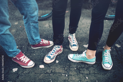 Fotografía Young rebel teenagers wearing casual sneakers, walking on dirty concrete
