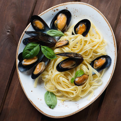 Wall Mural - Above view of tagliatelle with boiled mussels and green basil