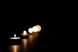 Candles arranged diagonally and burning in the darkness.