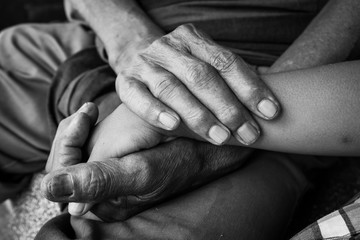 kids little boy hand touches and holds an old man wrinkled hands.