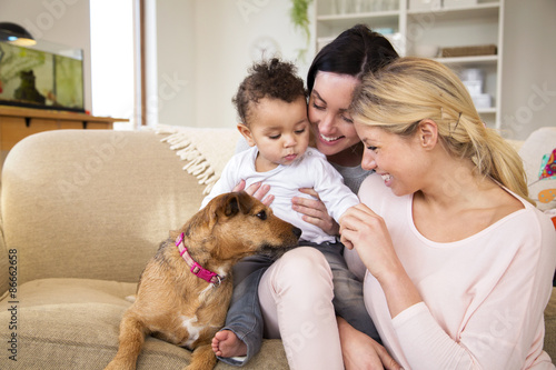 Same sex female couple sitting with their son and dog on the sofa in their home Fototapete