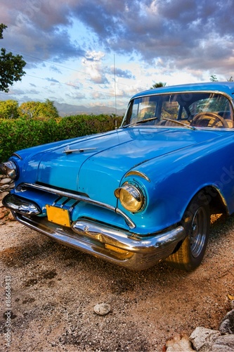 Nowoczesny obraz na płótnie Old blue American classic car at sunset time in mountainous and green outdoor setting in Trinidad, Cuba