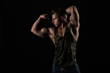 Portrait of a handsome muscular bodybuilder posing over black ba