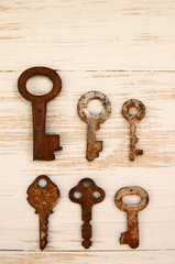 Old rusty keys to the locks on the wooden background. Collection of old lock keys