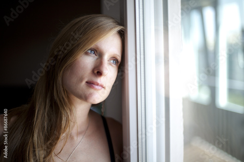 Valokuva Mujer rubia mirando pensativa por la ventana