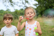 © goodluz - Kids in garden blowing soap bubbles