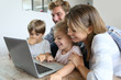 © goodluz - Parents with kids at home using laptop computer