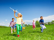 canvas print picture Small girl runs with kids and holds airplane toy