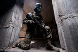 Fototapeta Młodzieżowe - Trooper in military camouflage holding a gun