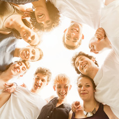 Wall Mural - Group of ten young teenagers friends gathered to form a circle in the park, embraced each other. Group seen from bottom to top, during a summer day in a park at sunset