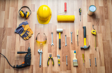 helmet, drill, hammer, work gloves and construction tools on a b