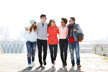 Wall Mural - happy teenage friends walking along city street