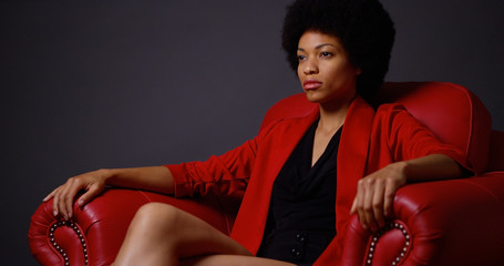 Strong attractive Black woman sitting in red chair