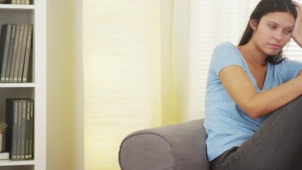 Wall Mural - Hispanic woman sitting on couch thinking