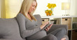 © rocketclips - Happy pregnant woman sitting on couch using tablet