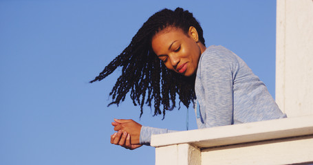 Wall Mural - Happy black woman leaning on rail smiling