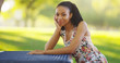© Mark Adams - Black woman sitting on a park bench smiling