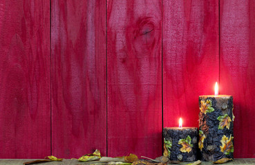 Wall Mural - Textured fall candles with leaves burning by antique red wood background