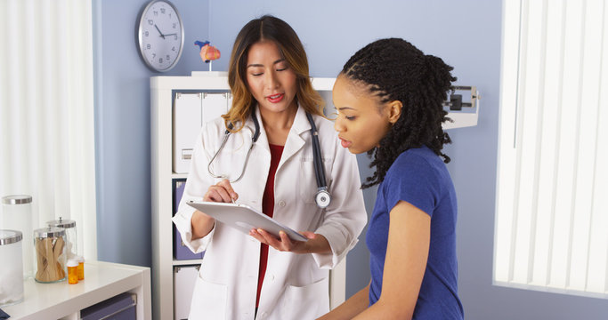 Wall Mural -  - African American patient explaining issues to Asian doctor using tablet