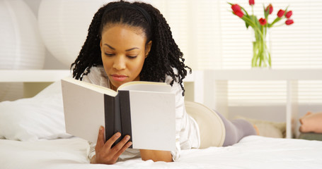 Wall Mural - Young black woman reading on bed