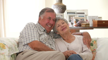 Wall Mural - Retired Senior Couple Sitting On Sofa At Home Together