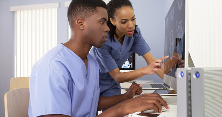 two african american medical specialists working together on computer