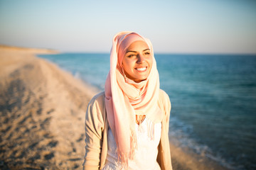 Young beautiful happy muslim woman outdoors portrait.Seaside,beach walk.Beautiful arab saudi woman face posing on the beach with the sea in the background