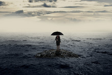 Woman With Umbrella Standing On The Rock In The Middle Of The Sea