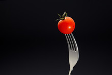 Fresh Tomato On A Fork Isolated On Black Background.