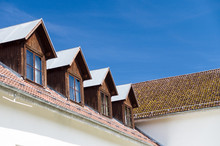 Tile Roof And Windows Of Mansard Rooms Against Blue Sky