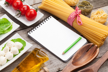 Tomatoes, mozzarella, pasta and green salad leaves with notepad