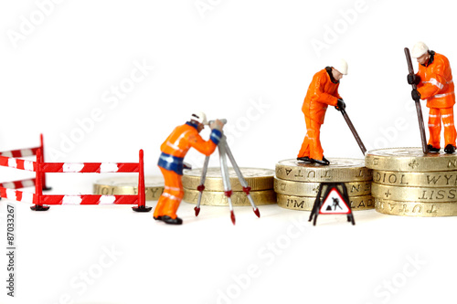 Fotografie, Obraz Miniature construction workers pound coins