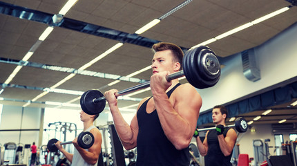 Canvas Print - group of men flexing muscles with barbell in gym