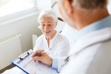 Canvas Print - senior woman and doctor with clipboard at hospital