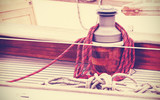 Fototapeta Lawenda - Vintage toned winch with rope on sailing boat.