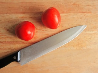 Close up knife and tomato on wooden table