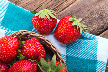 fresh strawberries in a bowl with napkin on old wooden backgroun