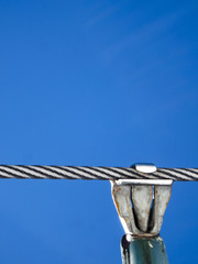 Close up of a steel cable and the attachment for a ski resort chair lift against blue sky